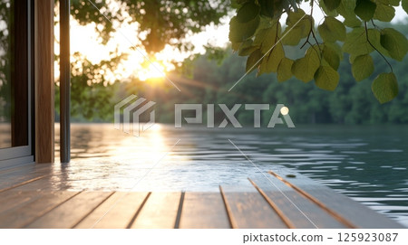 Wooden dock extends over calm lake water at sunset, with tree branches overhead 125923087