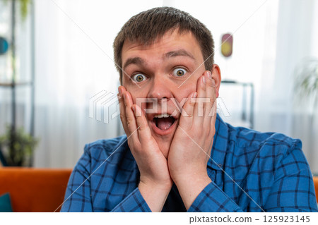 Excited shocked amazed young man surprised looking at camera with big eyes wow emotion good win news Excited shocked amazed young man surprised looking at camera with big eyes wow emotion good win news 125923145