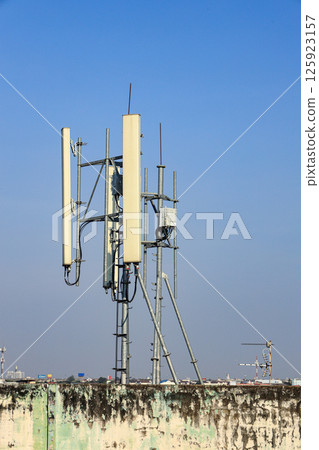 Wireless Communication Antenna pole, Mobile phone mast antenna pole on top of dilapidated building. 125923157