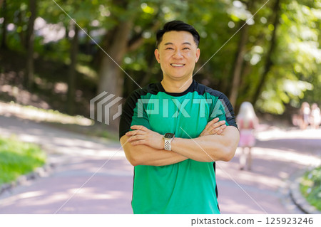 Portrait of happy Japanese sporty man athlete healthy lifestyle posing looking at camera in park 125923246