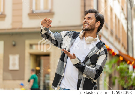 Cheerful rich Indian man showing wasting throwing money around hand gesture standing on city street Cheerful rich Indian man showing wasting throwing money around hand gesture standing on city street 125923398