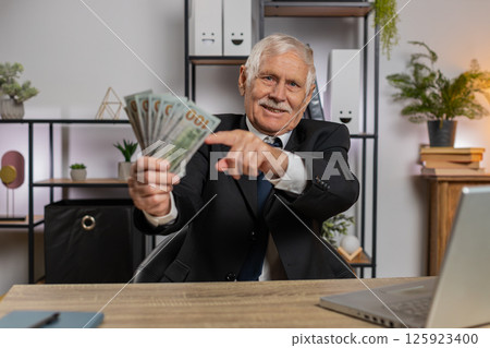 Rich grandfather businessman working on laptop counting money cash, calculate profit at home office 125923400