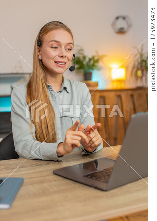 Mature female customer service representative with headset using laptop computer at home office desk 125923473