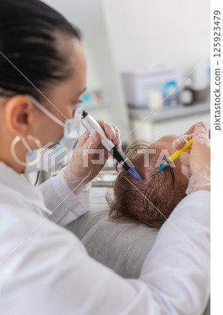 Trichologist doing man improve hair growth procedure, dermapen microneedling, vitamin injections 125923479