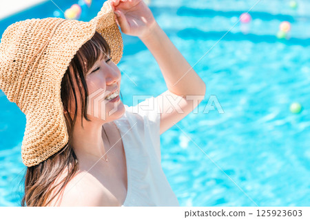 Young Asian woman sunbathing by the pool 125923603