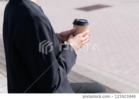 Young woman in a suit drinking coffee outdoors 125923846
