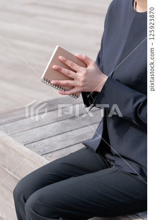 一位身穿西裝的年輕女子正在合上記事本 125923870