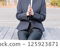 一位身穿西裝的年輕女子正在合上記事本 125923871