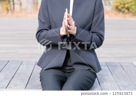 一位身穿西裝的年輕女子正在合上記事本 125923871
