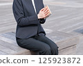 一位身穿西裝的年輕女子正在合上記事本 125923872