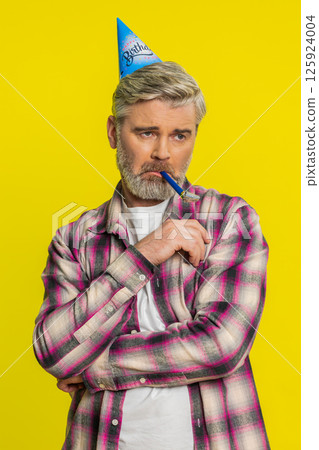 Mature man lonely birthday party cone hat, blower bored mood solitude celebration upset tired bored 125924004