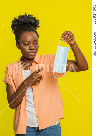 African American woman holding medical mask, gesturing explanation, focused expression, health topic 125924006