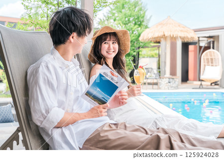 一對夫婦在旅行中坐在度假酒店的池畔椅上 125924028