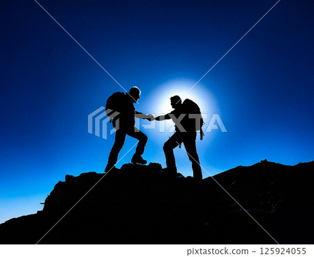 Silhouetted climbers helping each other on a mountain trail 125924055