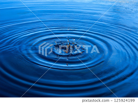 深藍色水面上的一滴水，一個物體落在水面上，倒水時形成一個水柱和一個水冠，濺起水花，泛起漣漪2 125924199
