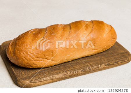 Freshly baked bread on cutting board against white wooden background. perspective view bread with copy space Freshly baked bread on cutting board against white wooden background. perspective view bread with copy space 125924278