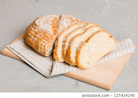 Assortment of freshly sliced baked bread with napkin on rustic table top view. Healthy unleavened bread. French bread slice Assortment of freshly sliced baked bread with napkin on rustic table top view. Healthy unleavened bread. French bread slice 125924290