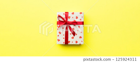 Gift box with red ribbon and heart on yellow background, top view with copy space for text Gift box with red ribbon and heart on yellow background, top view with copy space for text 125924311