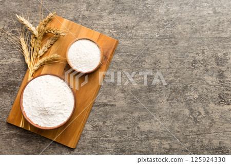 Flat lay of Wheat flour in wooden bowl with wheat spikelets on colored background. world wheat crisis 125924330