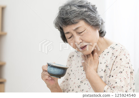 Senior woman who has difficulty swallowing dysphagia 125924540