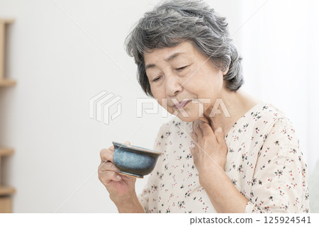 Senior woman who has difficulty swallowing dysphagia Senior woman who has difficulty swallowing dysphagia 125924541