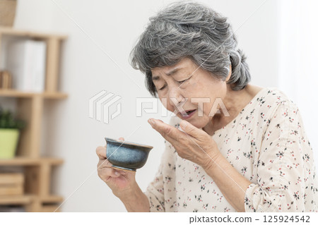 Senior woman who has difficulty swallowing dysphagia 125924542