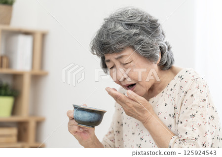 Senior woman who has difficulty swallowing dysphagia 125924543
