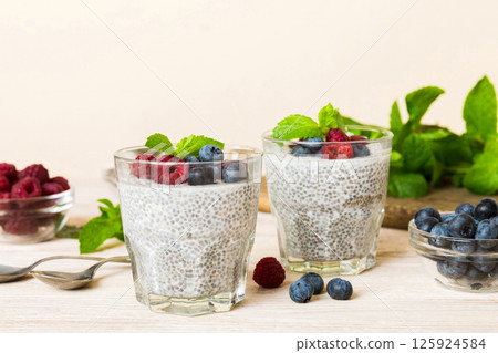 Healthy breakfast or morning with chia seeds vanilla pudding raspberry and blueberry berries on table background, vegetarian food, diet and health concept. Chia pudding with raspberry and blueberry 125924584