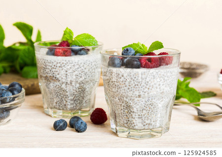 Healthy breakfast or morning with chia seeds vanilla pudding raspberry and blueberry berries on table background, vegetarian food, diet and health concept. Chia pudding with raspberry and blueberry 125924585