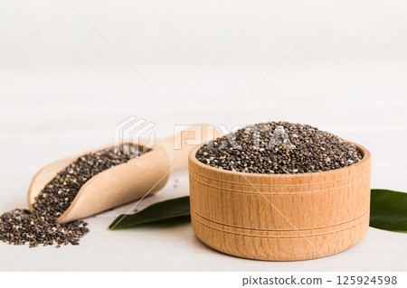 Chia seeds in bowl and spoon on colored background. Healthy Salvia hispanica in small bowl. Healthy superfood Chia seeds in bowl and spoon on colored background. Healthy Salvia hispanica in small bowl. Healthy superfood 125924598