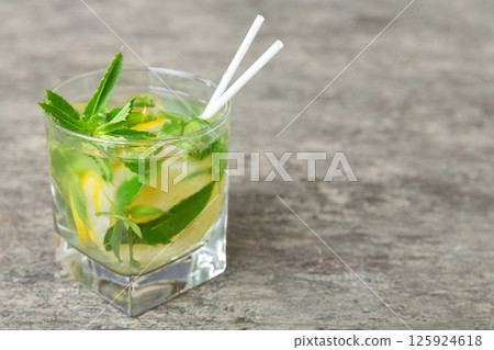 Mojito cocktail. Refreshing mojito cocktail with lime, lemon and mint in a tall glass with a stick Mojito cocktail. Refreshing mojito cocktail with lime, lemon and mint in a tall glass with a stick 125924618