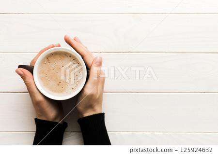 Minimalistic style woman hand holding a cup of coffee on Colored background. Flat lay, top view cappuccino cup. Empty place for text, copy space. Coffee addiction. Top view, flat lay Minimalistic style woman hand holding a cup of coffee on Colored background. Flat lay, top view cappuccino cup. Empty place for text, copy space. Coffee addiction. Top view, flat lay 125924632