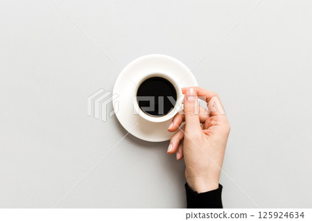 Minimalistic style woman hand holding a cup of coffee on Colored background. Flat lay, top view espresso cup. Empty place for text, copy space. Coffee addiction. Top view, flat lay 125924634