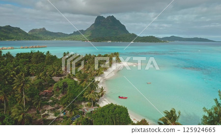 Stunning drone footage revealing the idyllic beauty of Bora Bora, featuring crystal-clear turquoise waters, pristine white sand beaches, and lush tropical vegetation. Travel tropical vacation concept 125924665