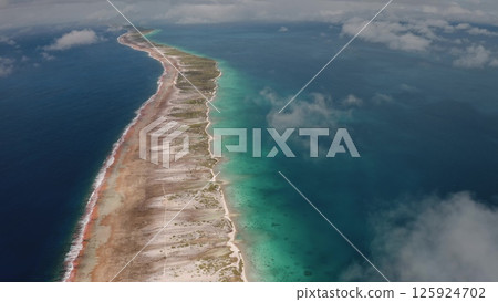 Overhead perspective of Rangiroa, largest atoll in Tuamotus archipelago, stunning turquoise lagoon and vibrant coral reefs. High angle over the clouds flight. Remote wild nature exotic summer travel. Overhead perspective of Rangiroa, largest atoll in Tuamotus archipelago, stunning turquoise lagoon and vibrant coral reefs. High angle over the clouds flight. Remote wild nature exotic summer travel. 125924702