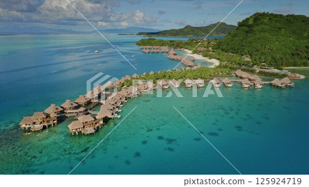 Aerial view zoom out panorama of luxurious overwater bungalows lining the tropical island shore, nestled in vibrant turquoise lagoon in Bora Bora. Popular tourist destination, exotic summer travel 125924719
