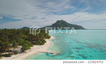 Aerial view of Maupiti island, French Polynesia, with turquoise lagoon, white beach, lush green vegetation, and mount Teurafaatui, creating a tropical paradise under a cloudy sky. Exotic summer travel Aerial view of Maupiti island, French Polynesia, with turquoise lagoon, white beach, lush green vegetation, and mount Teurafaatui, creating a tropical paradise under a cloudy sky. Exotic summer travel 125924752