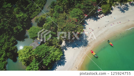 Thailand tropical island stony coastline landscape. Aerial view two traditional long tail boats, turquoise waters, pristine white sand beach, tourists relax and enjoy remote wild nature paradise Thailand tropical island stony coastline landscape. Aerial view two traditional long tail boats, turquoise waters, pristine white sand beach, tourists relax and enjoy remote wild nature paradise 125924755