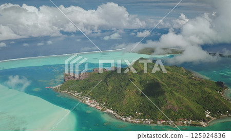 Wild Maupiti island in French Polynesia. Aerial drone fly over green mountain hills, turquoise coral reef lagoon, sky with white floating clouds. Remote nature travel background tropical paradise 125924836