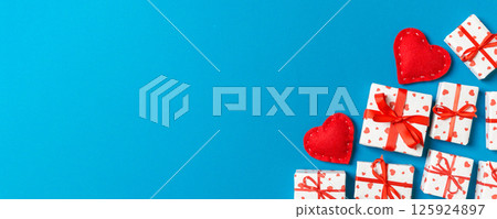 Holiday composition of gift boxes and red textile hearts on colorful background with empty space for your design. Top view of Valentine's Day concept Holiday composition of gift boxes and red textile hearts on colorful background with empty space for your design. Top view of Valentine's Day concept 125924897