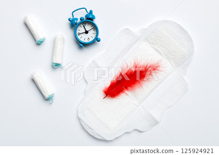 Ringing alarm clock with sanitary female tampons and menstrual sanitary pads. Medical concept of woman critical days and menstruation. Female daily hygiene. Copy space 125924921