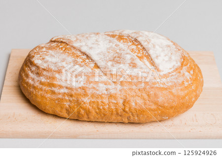Freshly baked bread on cutting board against white wooden background. perspective view bread with copy space Freshly baked bread on cutting board against white wooden background. perspective view bread with copy space 125924926