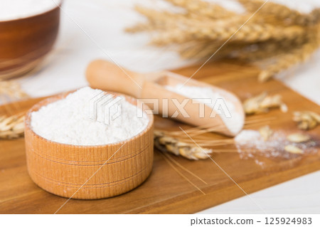 Flat lay of Wheat flour in wooden bowl with wheat spikelets on colored background. world wheat crisis Flat lay of Wheat flour in wooden bowl with wheat spikelets on colored background. world wheat crisis 125924983