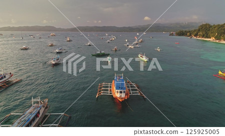 Aerial drone footage showing many colorful bangka boats crowding the sea near Cagban Beach, Boracay Island, Philippines, with the coast visible in the background 125925005