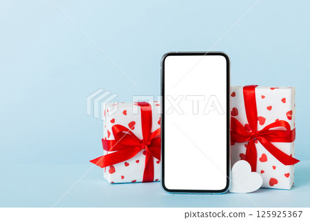 mobile phone with blank screen on colored background with hearts, calendar and gift box, valentine day concept perspertive view flat lay mobile phone with blank screen on colored background with hearts, calendar and gift box, valentine day concept perspertive view flat lay 125925367
