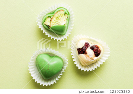 chocolate sweets in the form of a heart with fruits and nuts on a colored background. top view with space for text, holiday concept 125925380