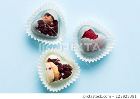 chocolate sweets in the form of a heart with fruits and nuts on a colored background. top view with space for text, holiday concept chocolate sweets in the form of a heart with fruits and nuts on a colored background. top view with space for text, holiday concept 125925381