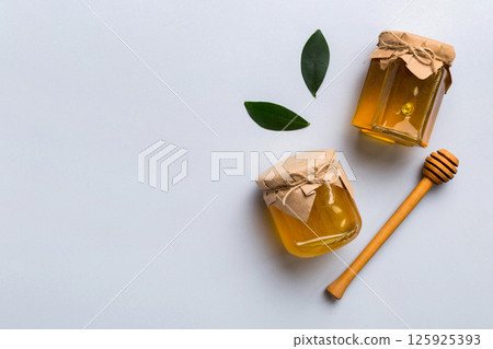 Honey jar with wooden honey dipper on white background top view with copy space. Delicious honey bottle Honey jar with wooden honey dipper on white background top view with copy space. Delicious honey bottle 125925393
