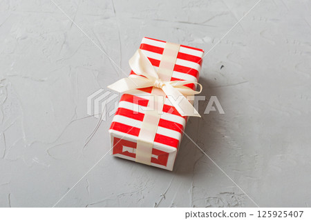 Wrapped christmas or other holiday handmade present in paper with colored ribbon. Present box, decoration of gift on table, top view with copy space Wrapped christmas or other holiday handmade present in paper with colored ribbon. Present box, decoration of gift on table, top view with copy space 125925407