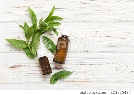 Natural Mint Essential Oil in a Glass Bottle. organic cosmetics with herbal extracts of mint on colored background Natural Mint Essential Oil in a Glass Bottle. organic cosmetics with herbal extracts of mint on colored background 125925424